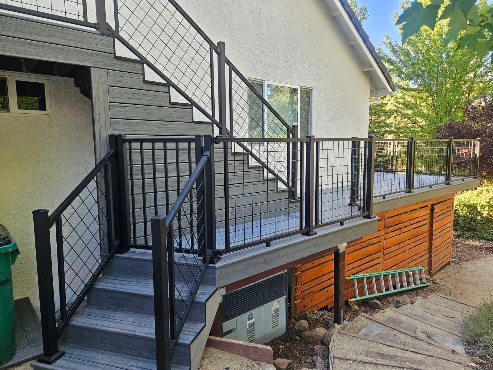 Gray composite deck with black metal railing and matching stairs, built by Cademartori Construction
